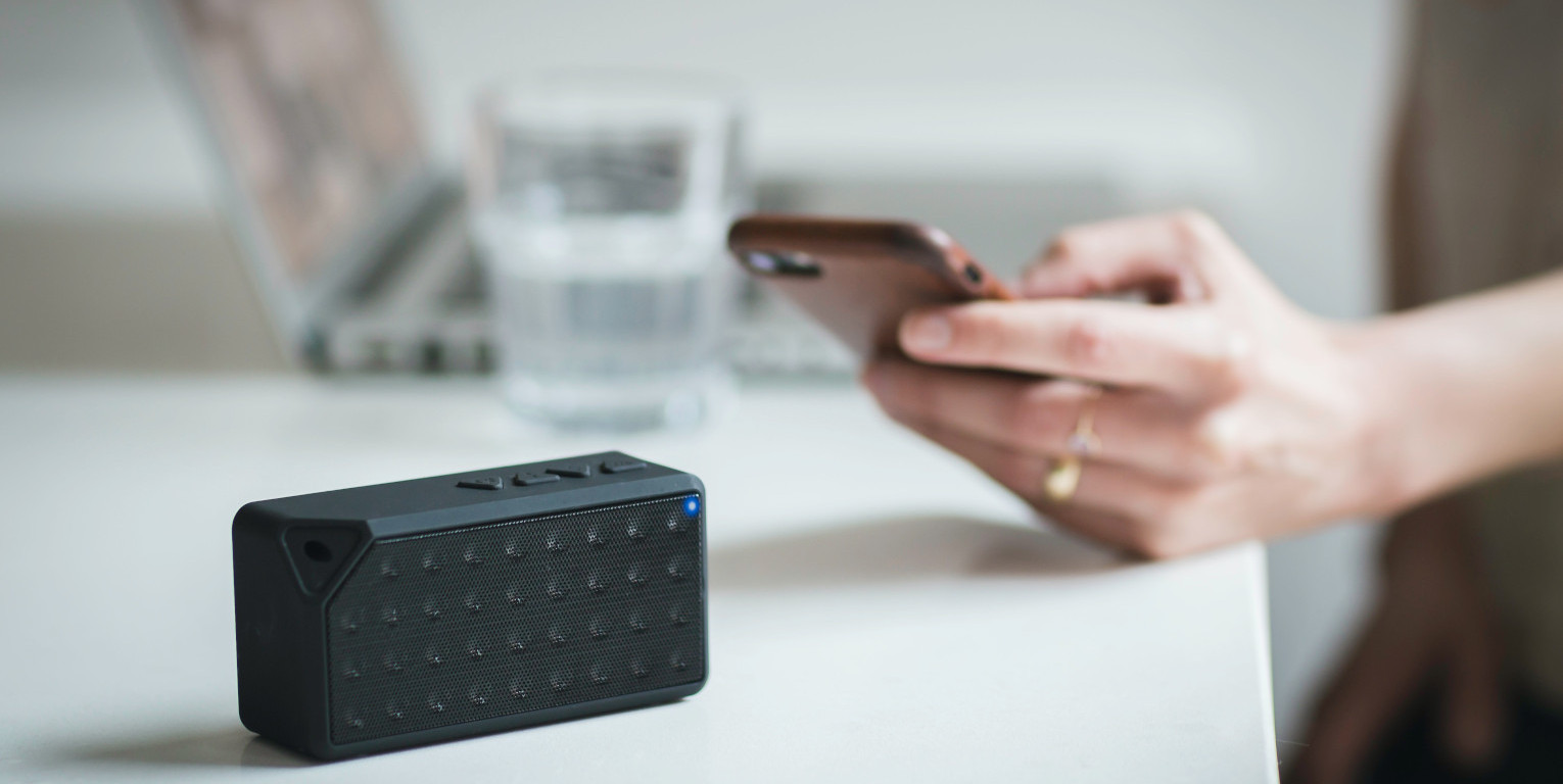 Bluetooth-Lautsprecher auf Tisch wird mit Smartphone gesteuert