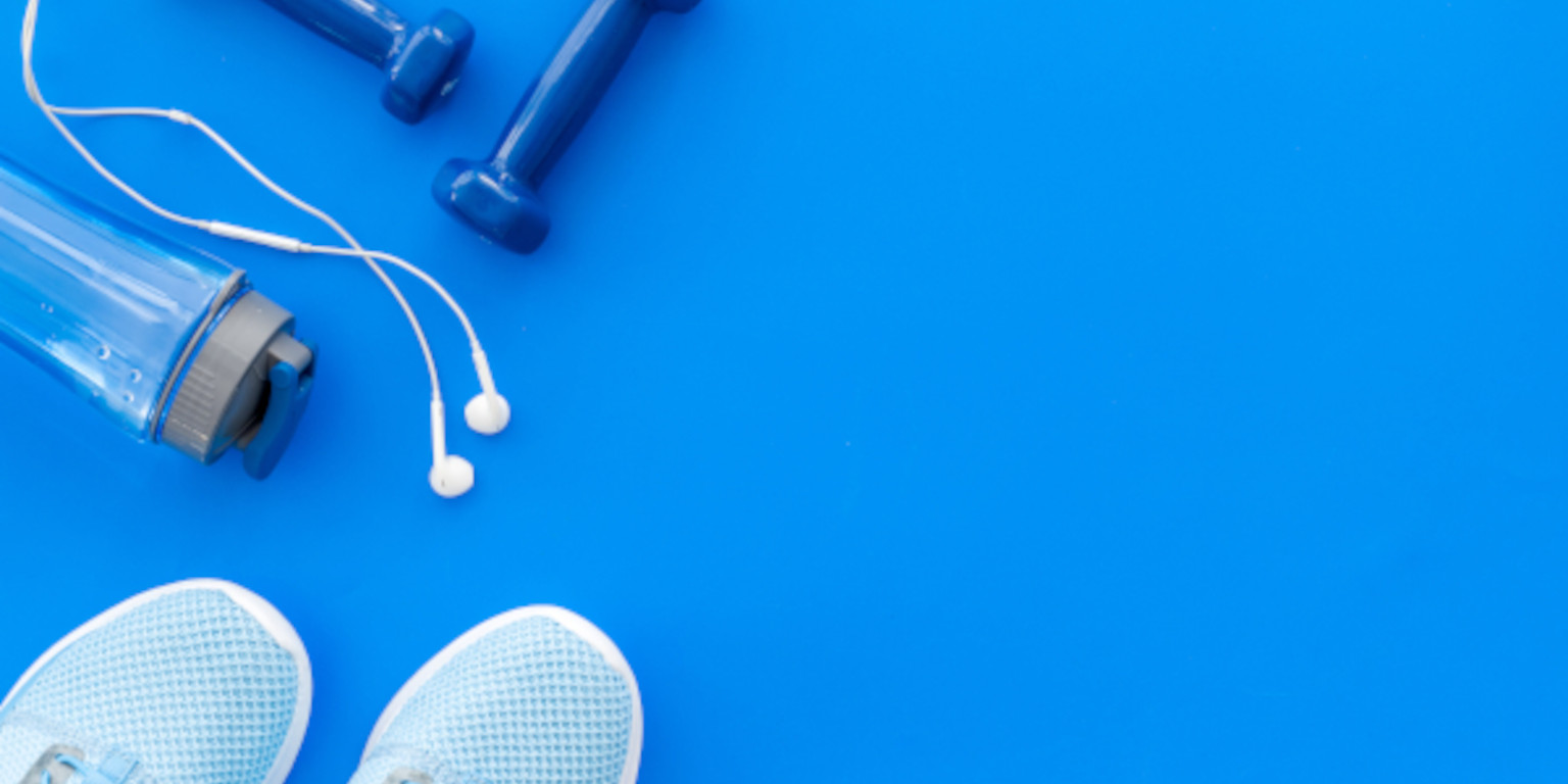 Kopfhörer mit Sportzeug vor blauem Hintergrund