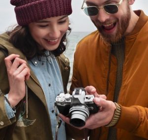 Frau und Mann betrachten Bilder auf einer Olympus-Systemkamera