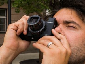 Mann blickt durch den ausfahrbaren Sucher der Canon G5 X Mark II