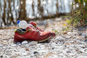 Sportschuhe mit Wasserflasche auf Kiesuntergrund