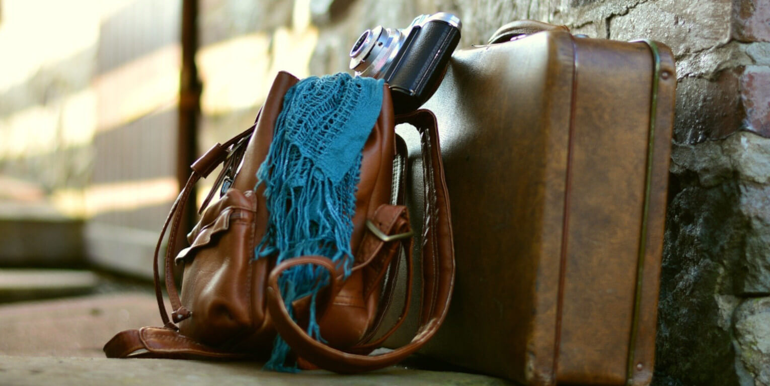 Ledertaschen mit Kamera an Steinwand