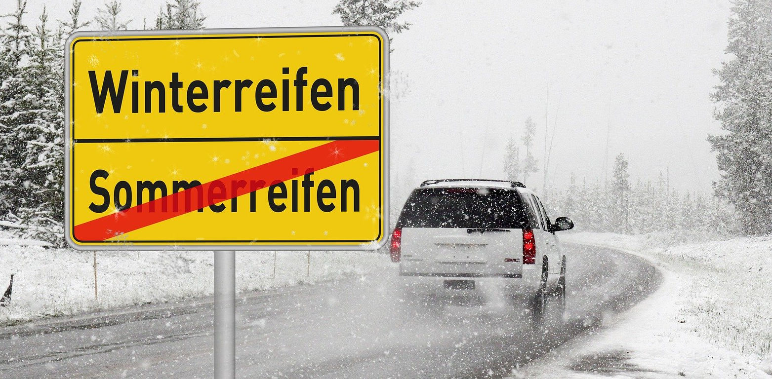 Schild Winterreifenpflicht in verschneiter Landschaft