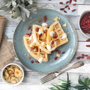 Waffeln mit Obst auf Teller und Tisch