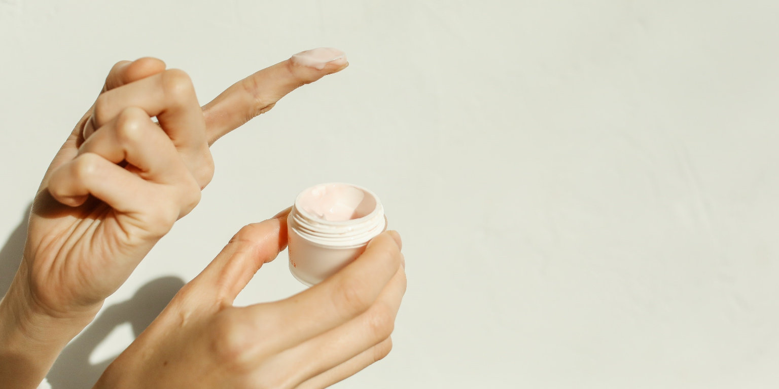 Eine Hautcreme wird einem Tiegel entnommen