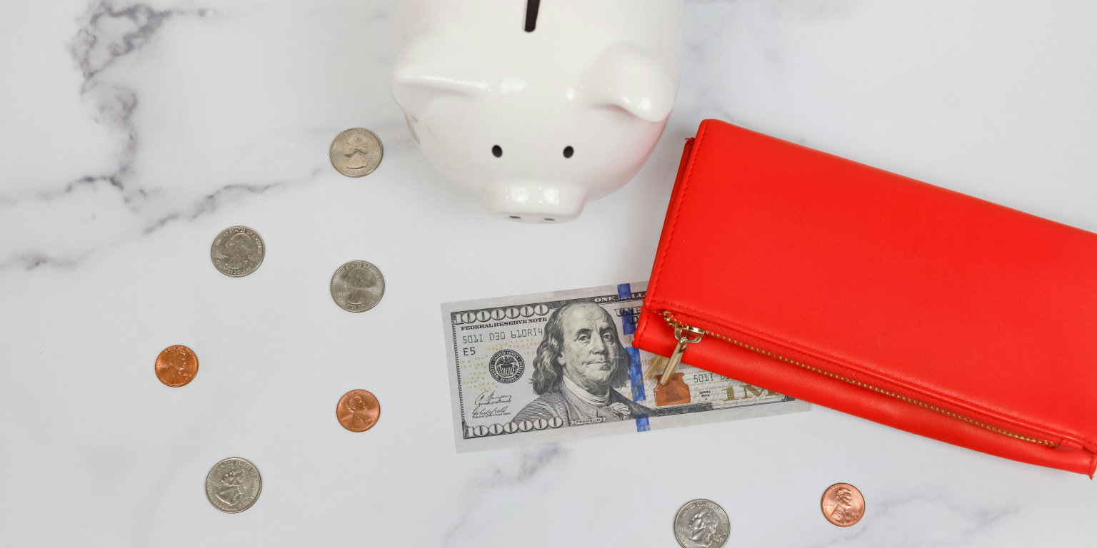 Sparschwein, Geld und rote Brieftasche auf weißer Mamor-Platte