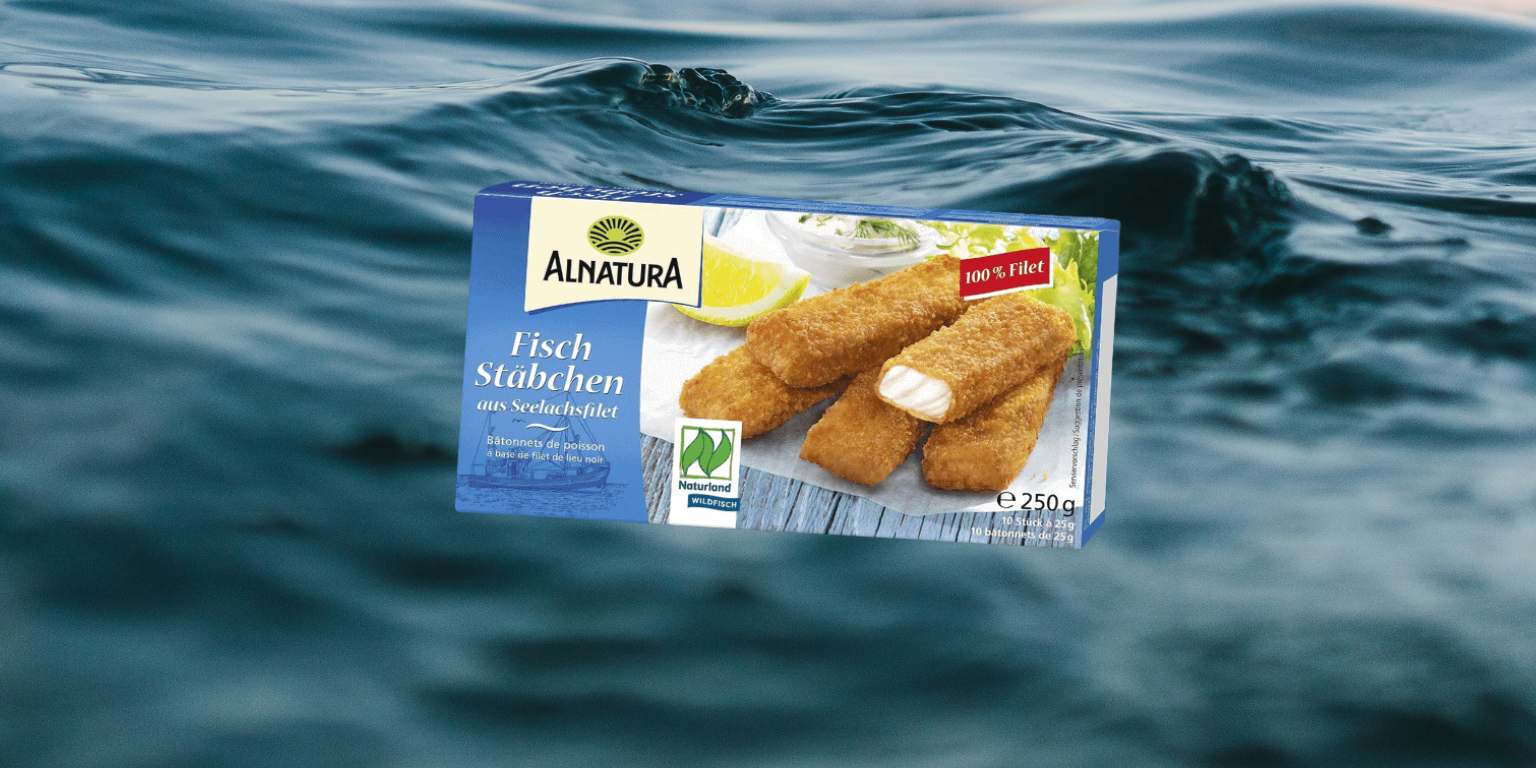 Eine Packung Fischstäbchen von Alnatura, im Hintergrund Meer
