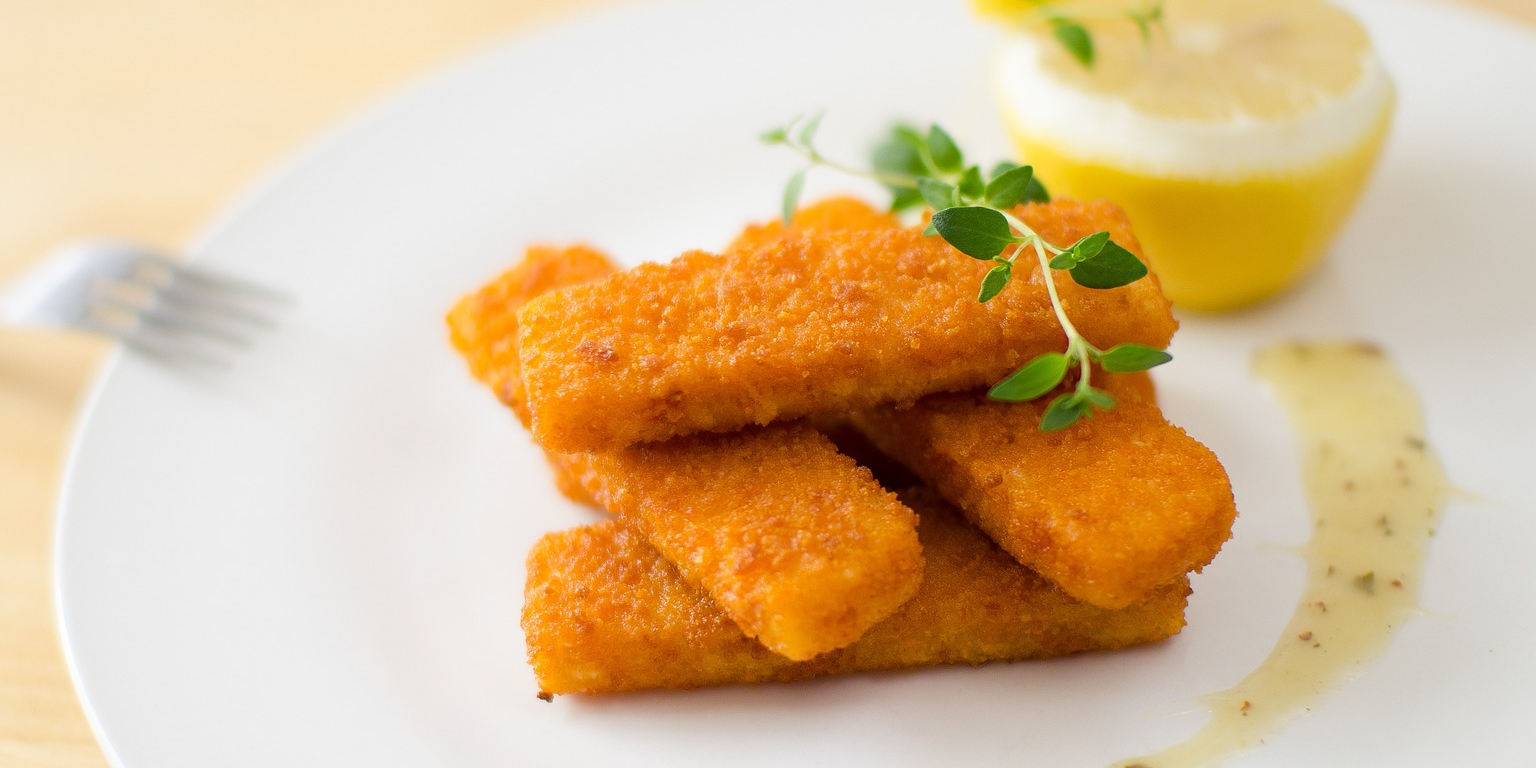 Fischstäbchen und eine Zitronenhälfte auf einem Teller
