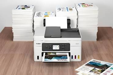 Stiftung Warentest Multifunktionsdrucker-Vergleich: „Mehrfach gut fürs Homeoffice“ Multifunktionsdrucker mit bedrucktem Papier im Hintergrund