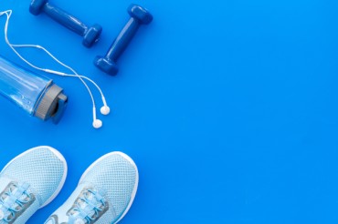 Sportkopfhörer: Mit Musik durchs Workout Turnschuhe, Hanteln und Sportkopfhörer auf blauem Untergrund